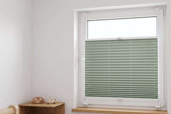 Kinderzimmer mit salbeigrünem Plissee, der Behang deckt die untere Fensterhälfte